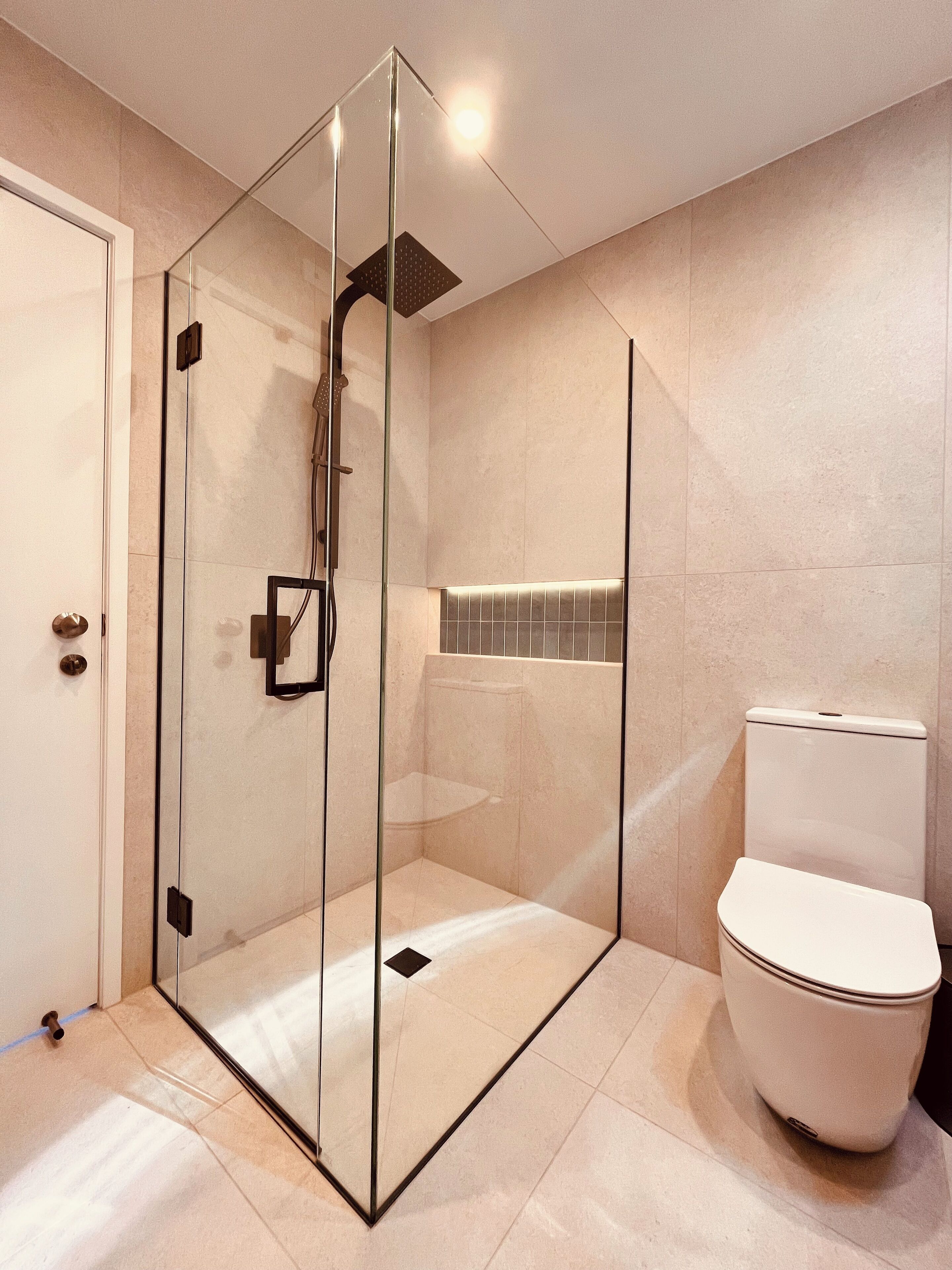 Un baño moderno con ducha de vidrio, inodoro y suelo de baldosas.