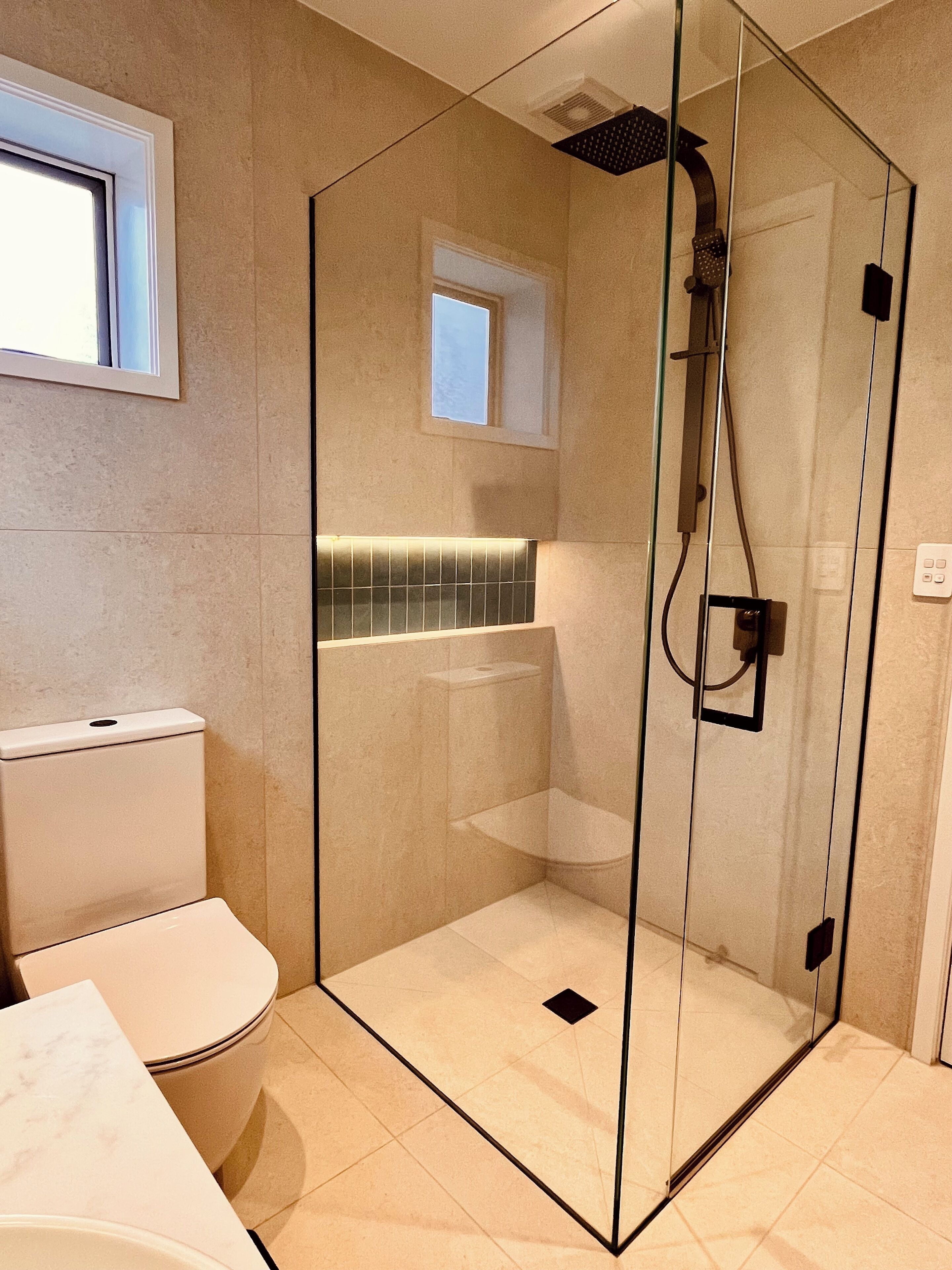 Un bagno moderno con doccia a vetro, un water e un lavandino.