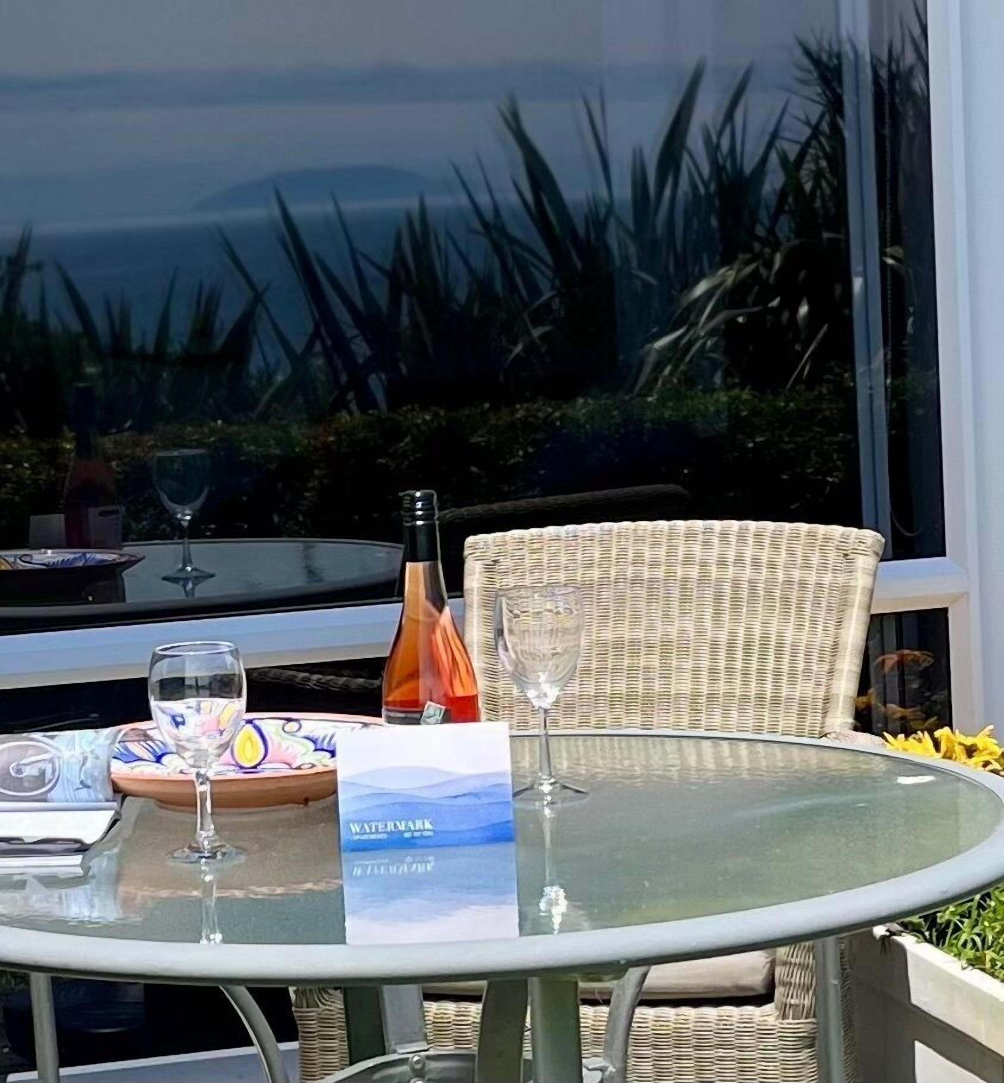 A table set with a bottle, glasses, and a placemat with a landscape design.