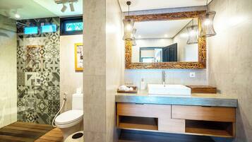 Un baño moderno con un espejo grande, tocador de madera y baldosas estampadas.