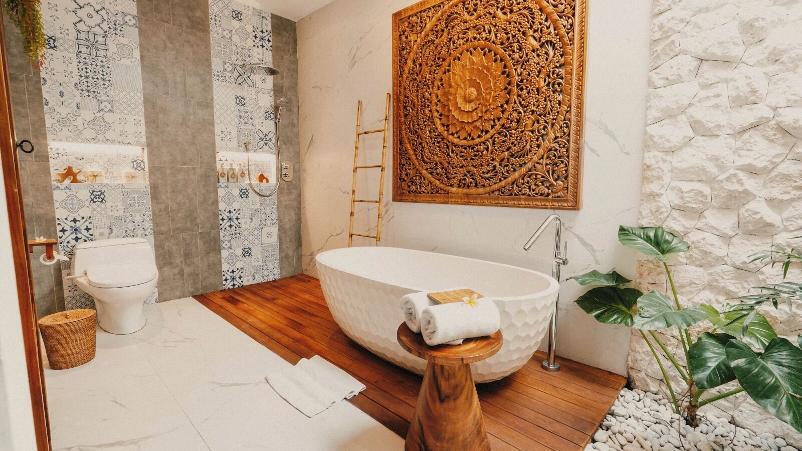 A bathroom with a freestanding bathtub, a toilet, a shower, and a large decorative wall piece.