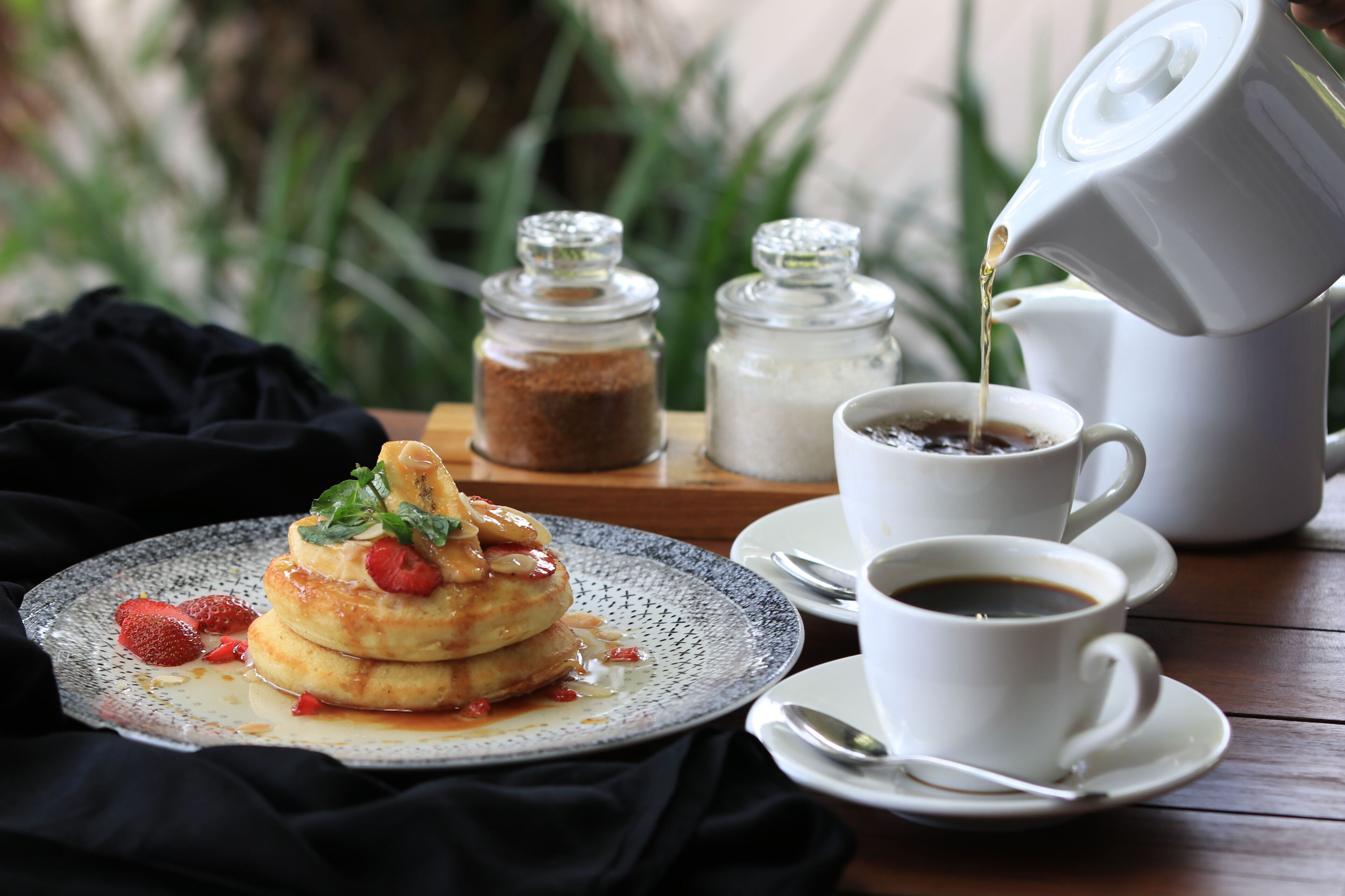 A breakfast setting with pancakes, strawberries, and coffee.