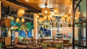 A modern restaurant interior with wooden furniture, hanging wicker lamps, and a bar area. - Natya Hotel Tanah Lot (Tabanan)