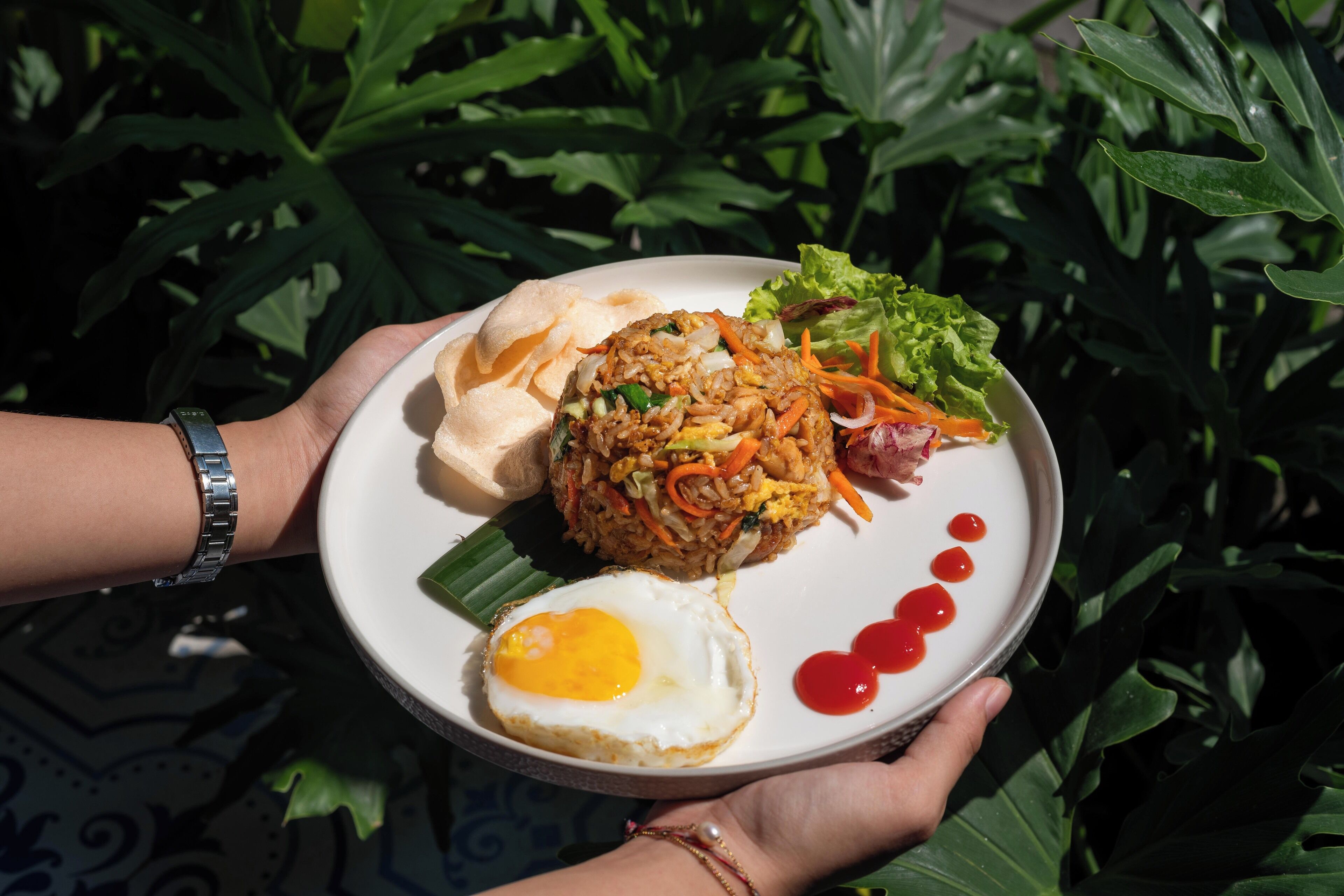 Une assiette de riz frit aux légumes, un œuf frit et une salade de laitue et de carottes en accompagnement.