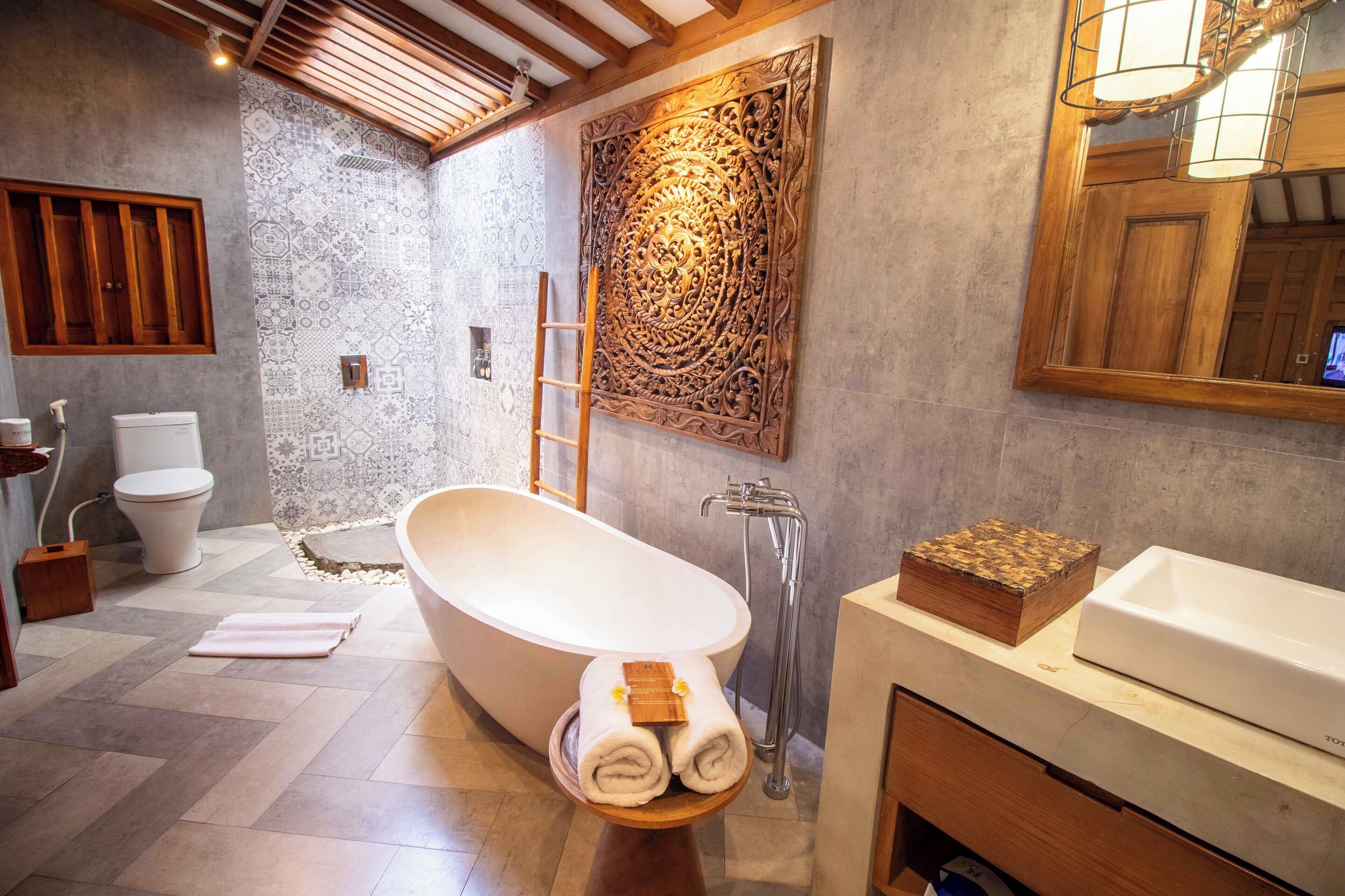 Un baño moderno con una bañera independiente, un tocador de madera y un espejo grande.