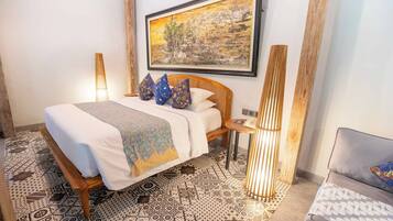 A neatly arranged bedroom with a bed, bedside tables, and a painting on the wall.