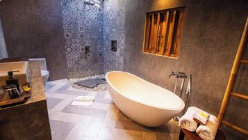 Un baño moderno con una bañera independiente, un tocador de madera y azulejos estampados en las paredes.