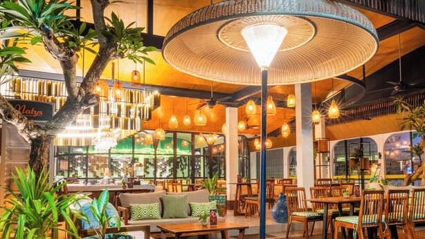 A restaurant with wooden furniture, hanging lights, and potted plants. - Natya Hotel Tanah Lot (Tabanan)