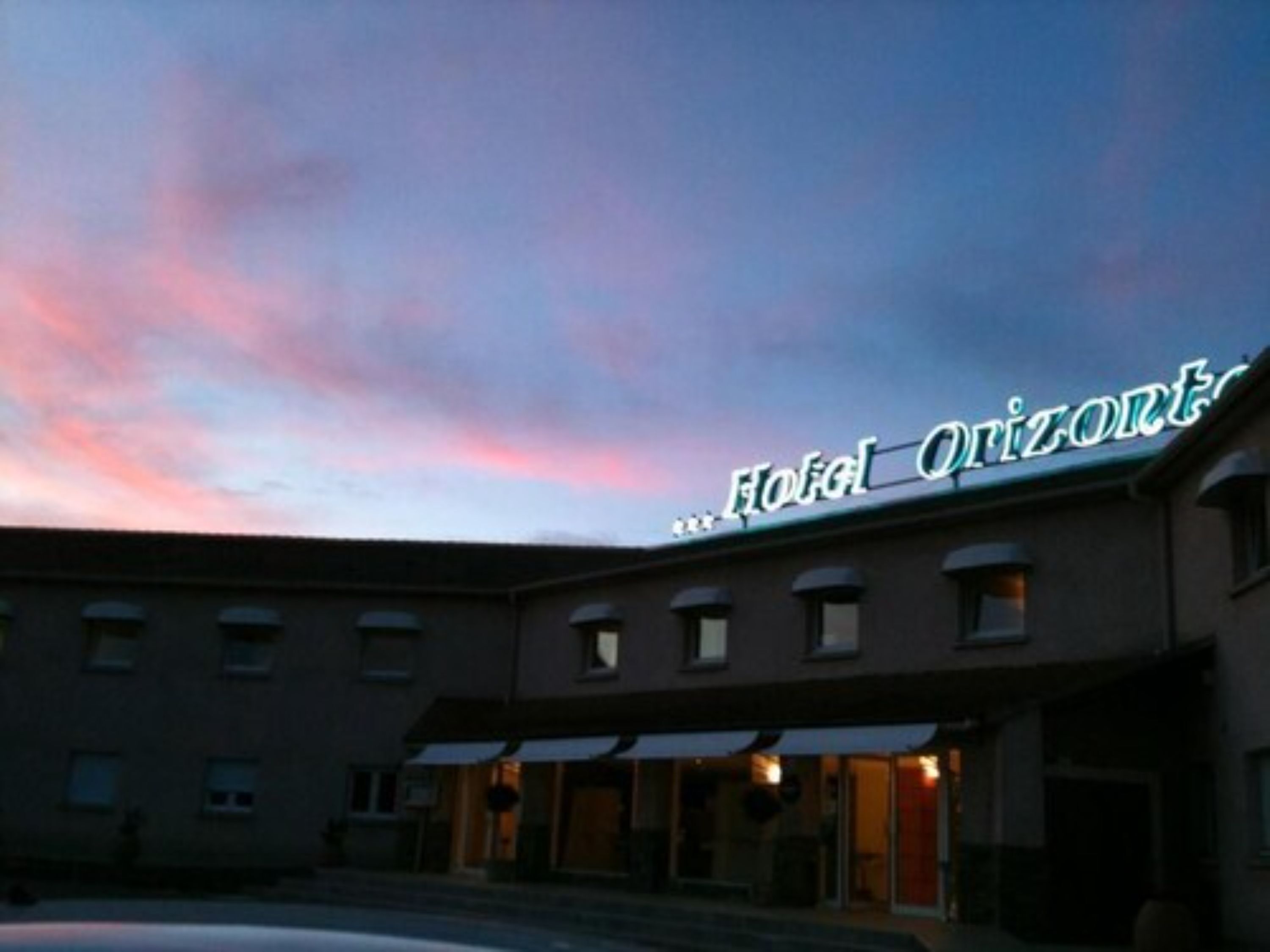 A hotel with a sign reading "Hotel...Quizzont." The building has multiple windows and a flat roof.