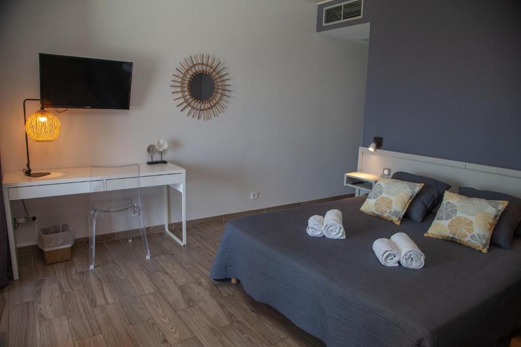 Una habitación de hotel con cama, escritorio, silla, televisor y un adorno en la pared.