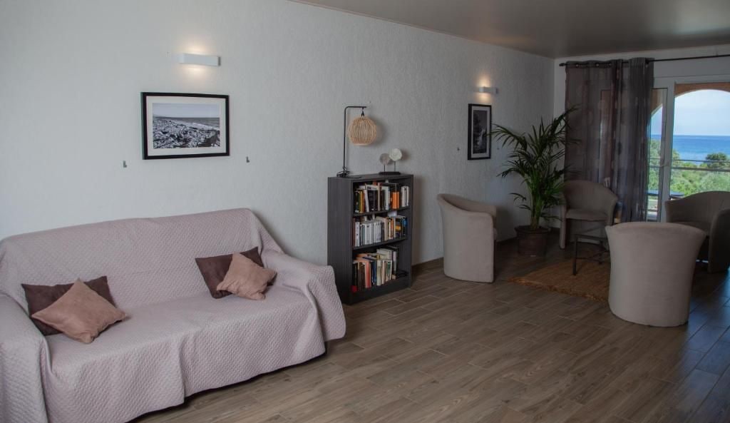 Een woonkamer met een bank, een boekenkast, een stoel en uitzicht op het landschap.
