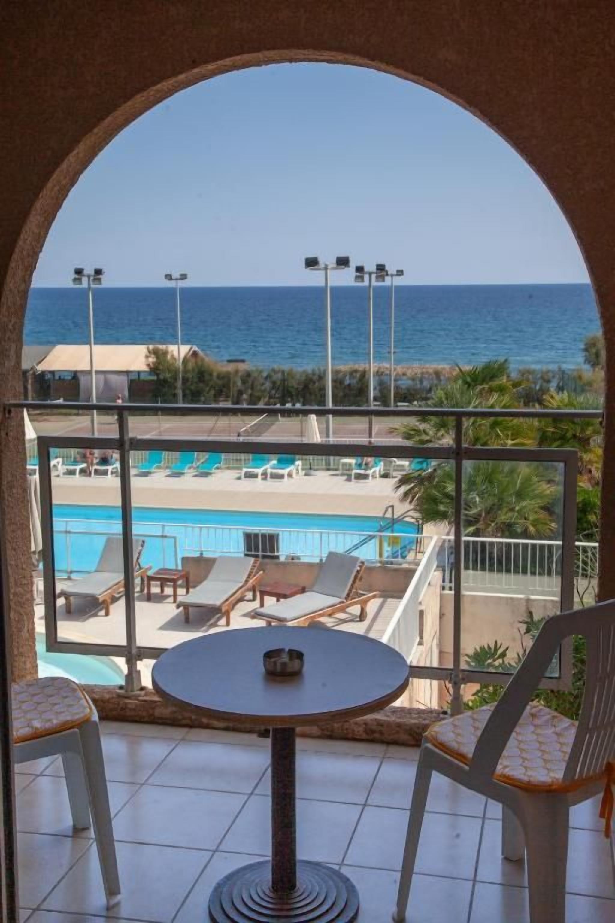 Un balcón con vistas a una piscina y al mar.