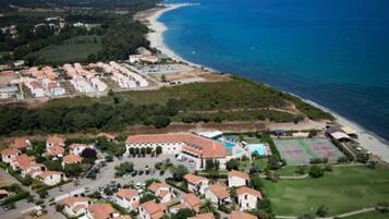 Luchtbeeld van een kustgebied met woonhuizen, een strand en een tennisbaan.