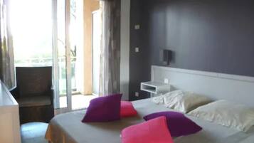 Una habitación de hotel con cama, almohadas, mesita de noche y vistas a través de una puerta.