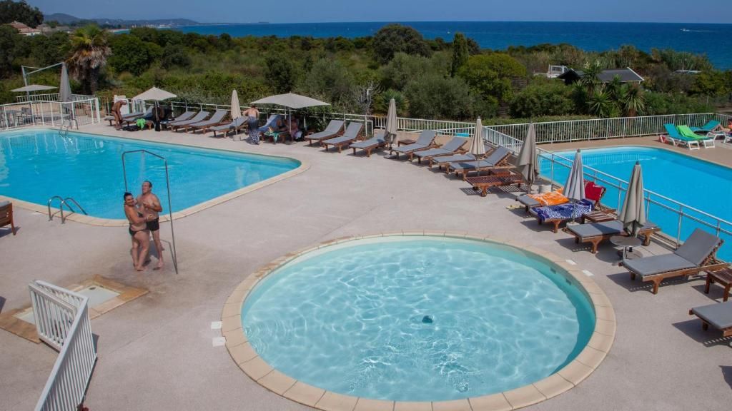 Un área de piscina con varias piscinas, tumbonas y sombrillas.