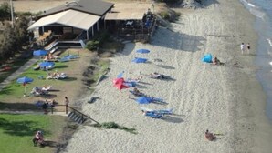 A beach with umbrellas, a building with a sloped roof, and a staircase leading down to the beach. - Hotel Orizonte (Cervione)