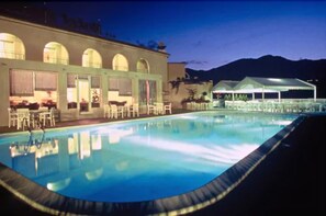 Una piscina al aire libre, sombrillas, sillones reclinables de piscina