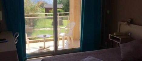 Una habitación de hotel con cama, escritorio y balcón con vistas.