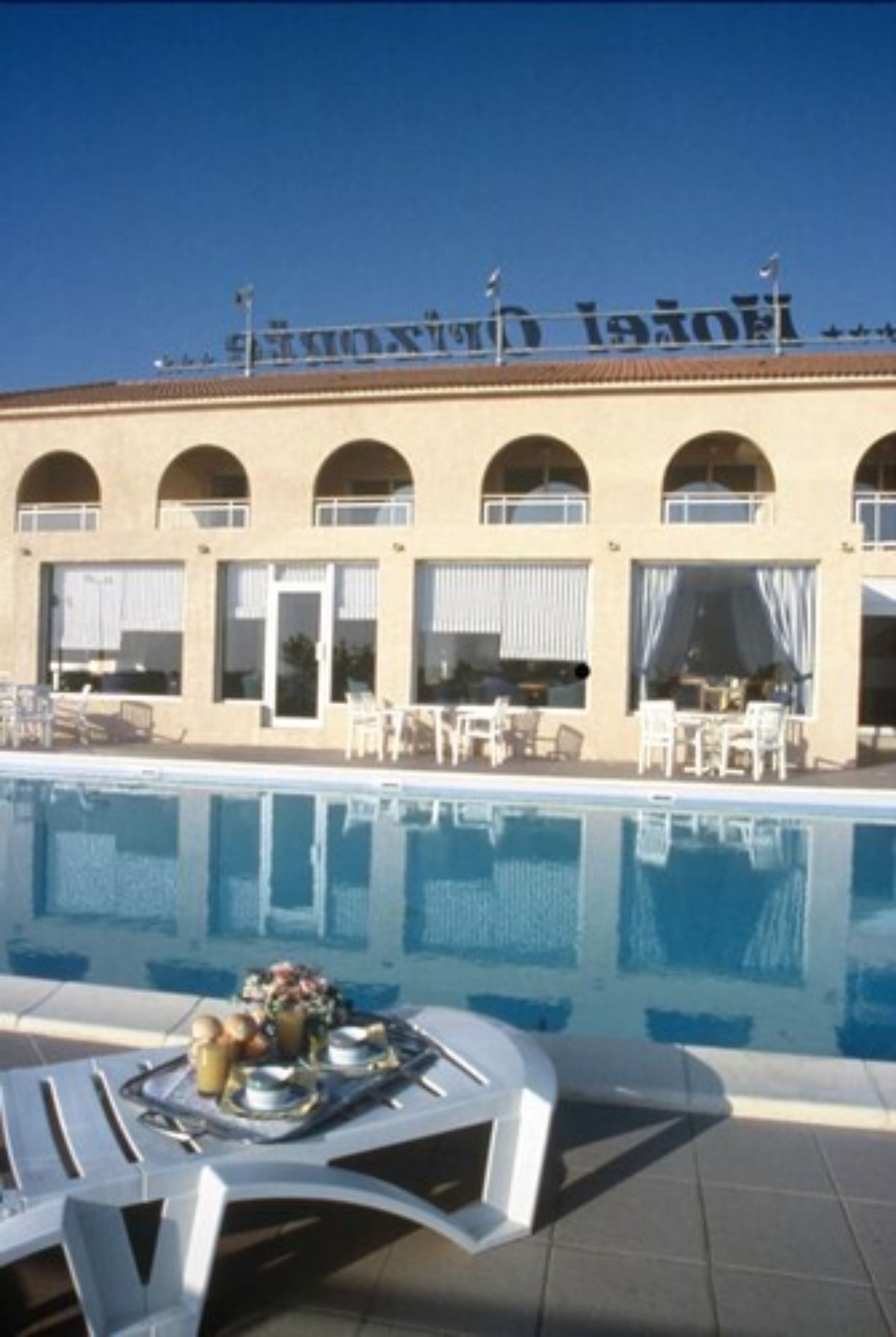 Um hotel com piscina, área de estar externa e uma placa com texto.