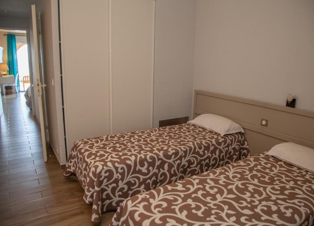A bedroom with two beds, a wooden floor, and a door leading to a hallway.