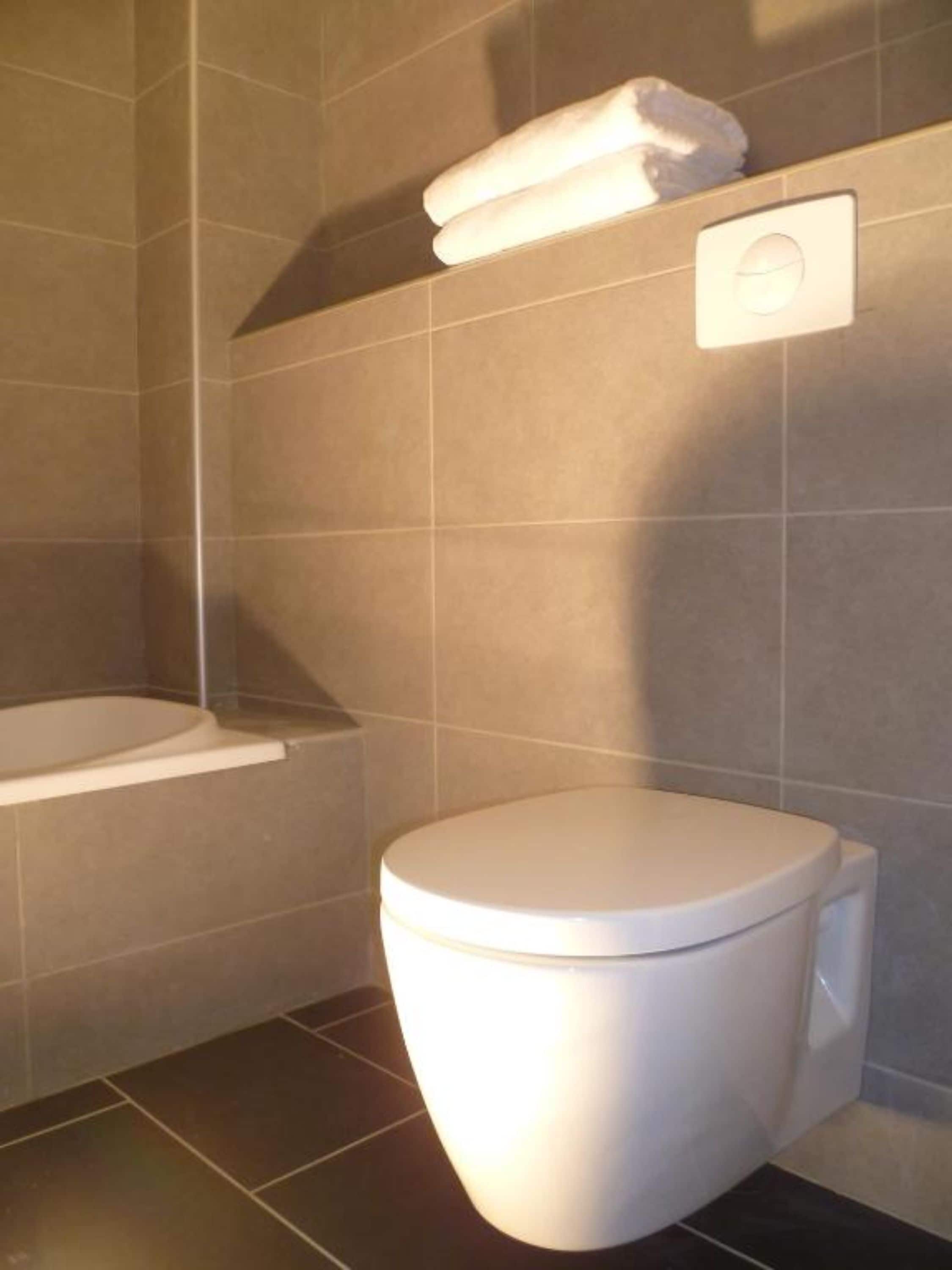 Une salle de bain moderne équipée de toilettes, d’une baignoire et d’un porte-serviettes.
