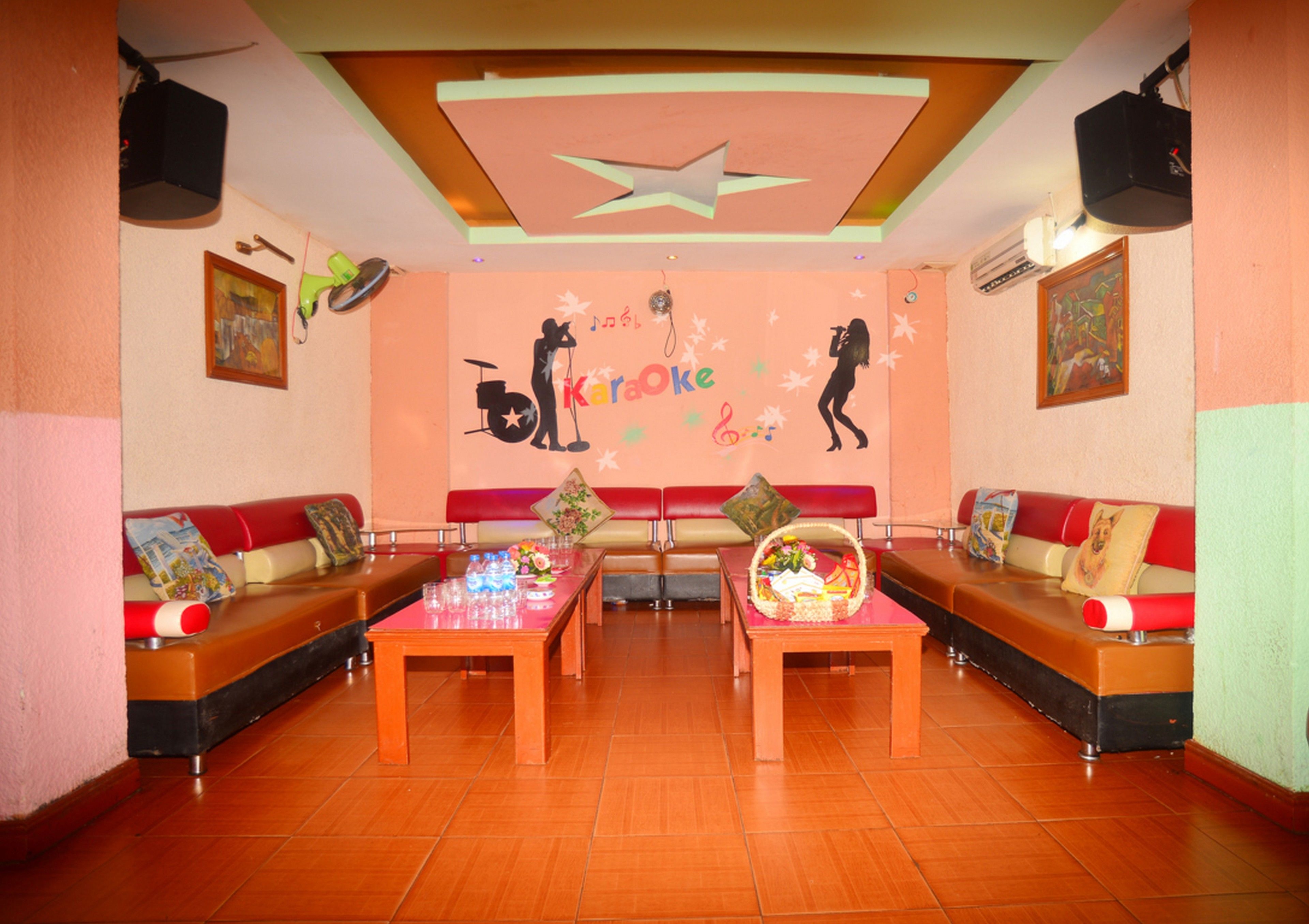 Una habitación con un escenario, sofás rojos y negros, y una mesa con un arreglo floral.