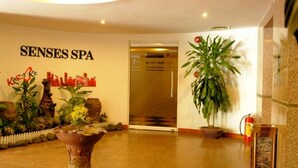 Uma área de recepção com uma placa indicando "SENSES SPA" e diversos vasos com plantas.
