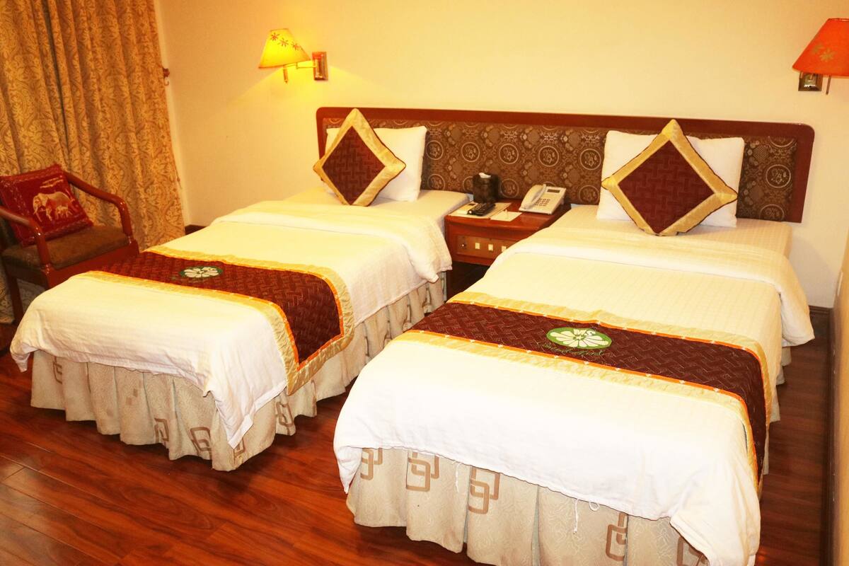 Une chambre d’hôtel avec deux lits, une table de chevet, une chaise et une lampe.