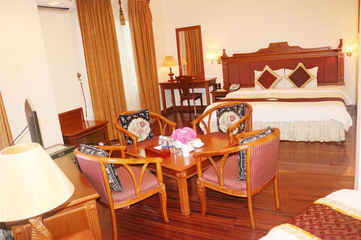 Une chambre d’hôtel comprenant un lit, un bureau avec une chaise, une table avec des chaises et une lampe.