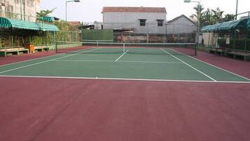 Ein Tennisplatz im Freien mit roter Belag und grünen Spiellinien.