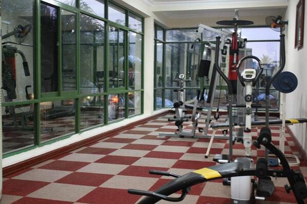 A gym with exercise equipment, large windows, and a checkered floor. - Central Hotel (Cam Thanh)