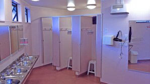 Un bagno pubblico con diversi lavandini, specchi e un asciugacapelli a parete.