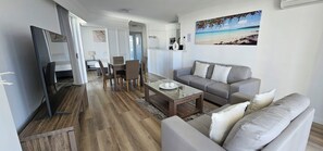 A modern living room with a sofa, coffee table, and dining area. - Broadbeach Holiday Apartments, Store 19 (Broadbeach)