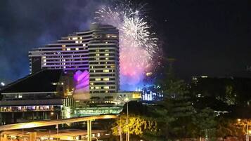 A multi-story building with illuminated windows and a bridge in the foreground.