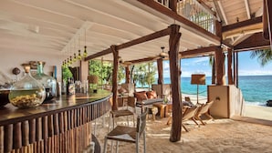 A beachside bar with wooden furniture, a view of the ocean, and a tropical setting. - Constance Tsarabanjina (Tsarabanjina)