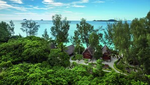 A tropical resort with thatched-roof cabins surrounded by lush greenery and a clear view of the turquoise sea. - Constance Tsarabanjina (Tsarabanjina)