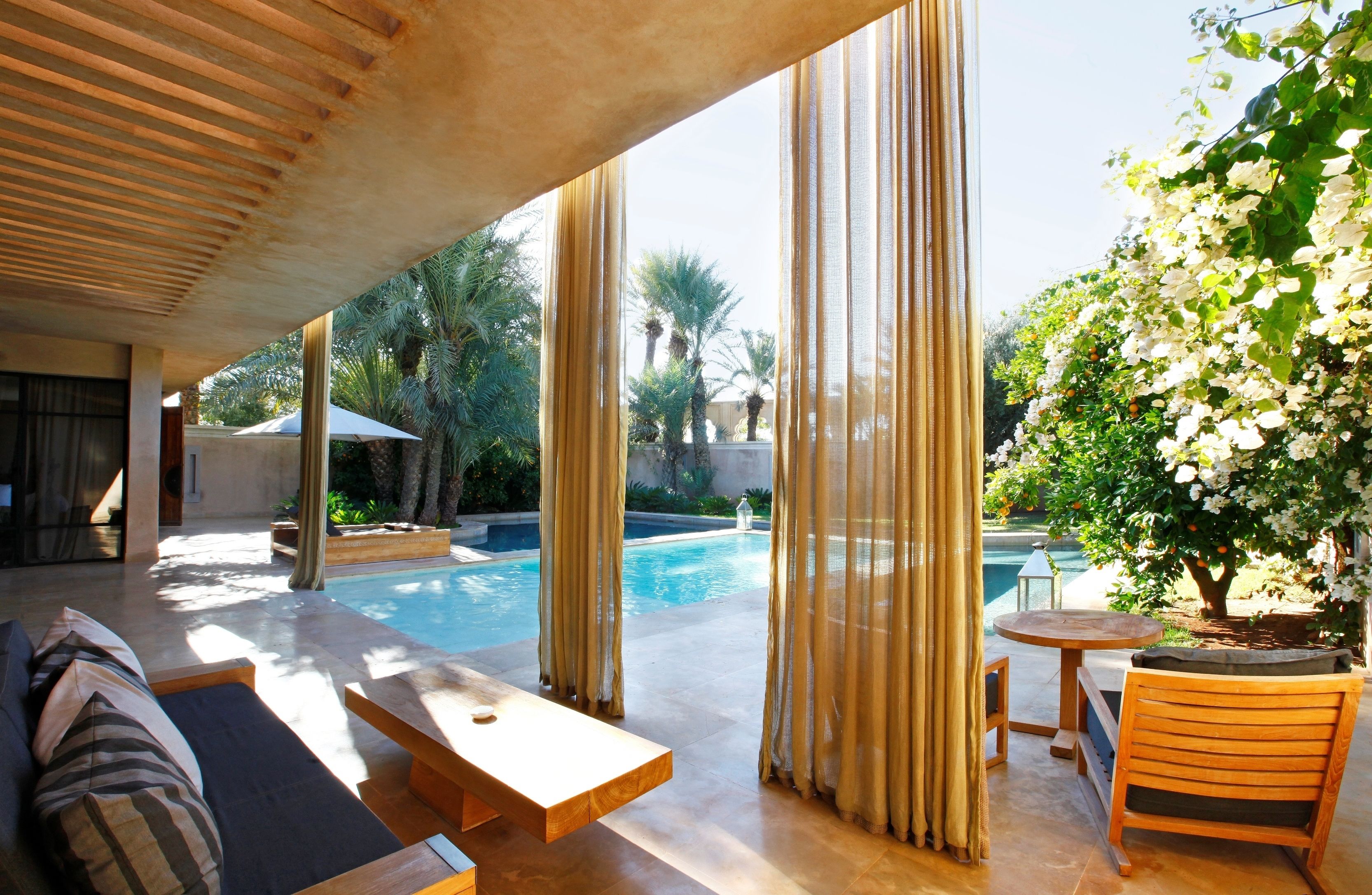 Zona junto a la piscina con un sofá, una mesa y una silla.