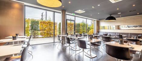 Uma sala de conferências moderna com grandes janelas, várias mesas e cadeiras.