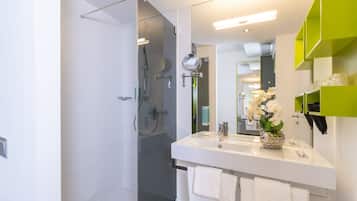 Un baño moderno con ducha envuelta en vidrio, un lavamanos blanco y un espejo.