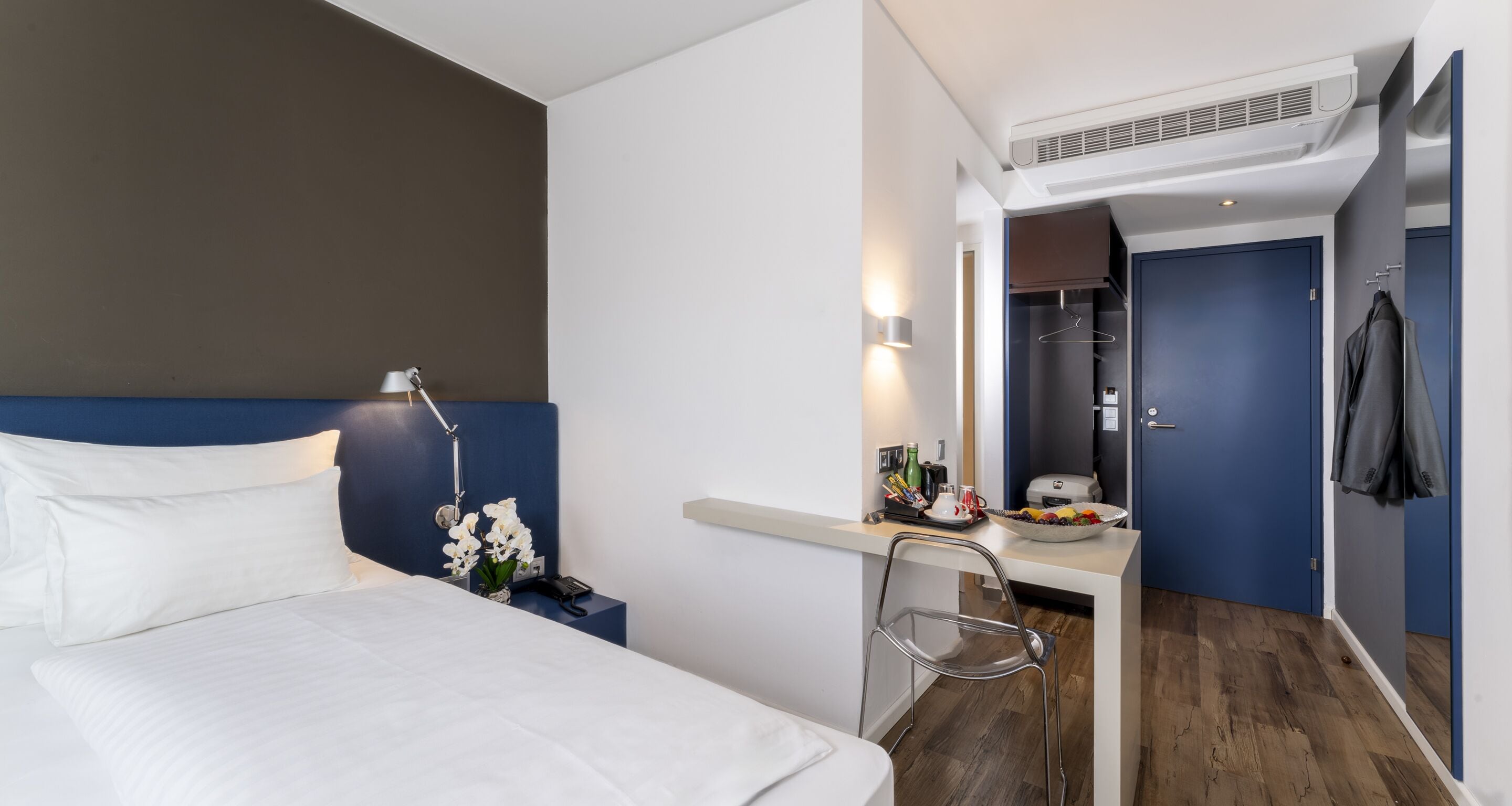 Une chambre d’hôtel équipée d’un lit, d’un bureau, d’une chaise et d’un petit coin cuisine.