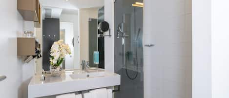 Een moderne badkamer met een wit wastafelmeubel, spiegel en douchecabine van glas.
