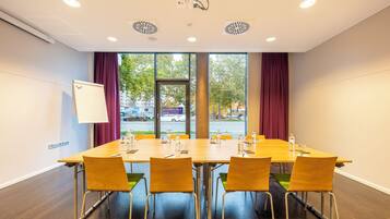 Une salle de conférence avec une longue table, quatre chaises et un tableau blanc au mur.