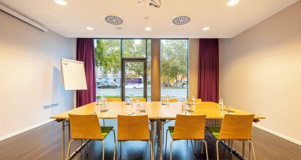 A conference room with a long table, four chairs, and a whiteboard on the wall. - PLAZA INN Graz Messe (Graz)