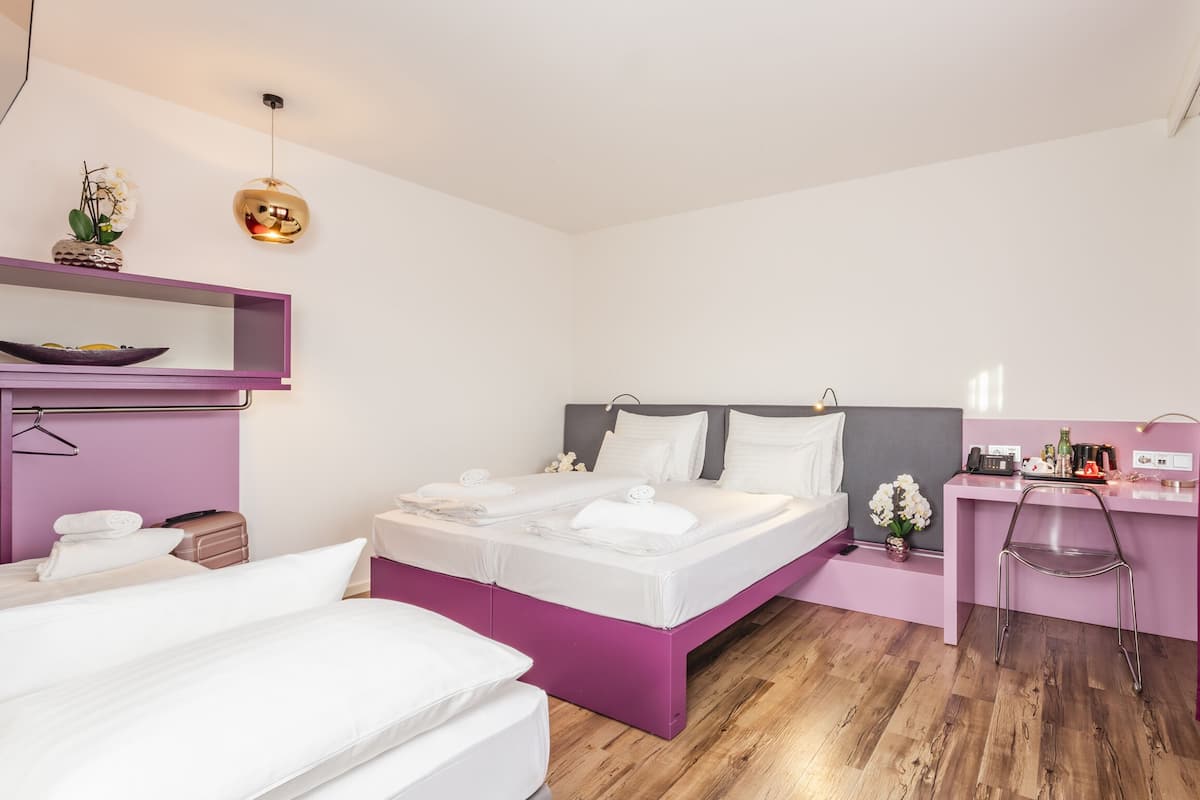 A modern hotel room with a large bed, a desk, and a vanity.