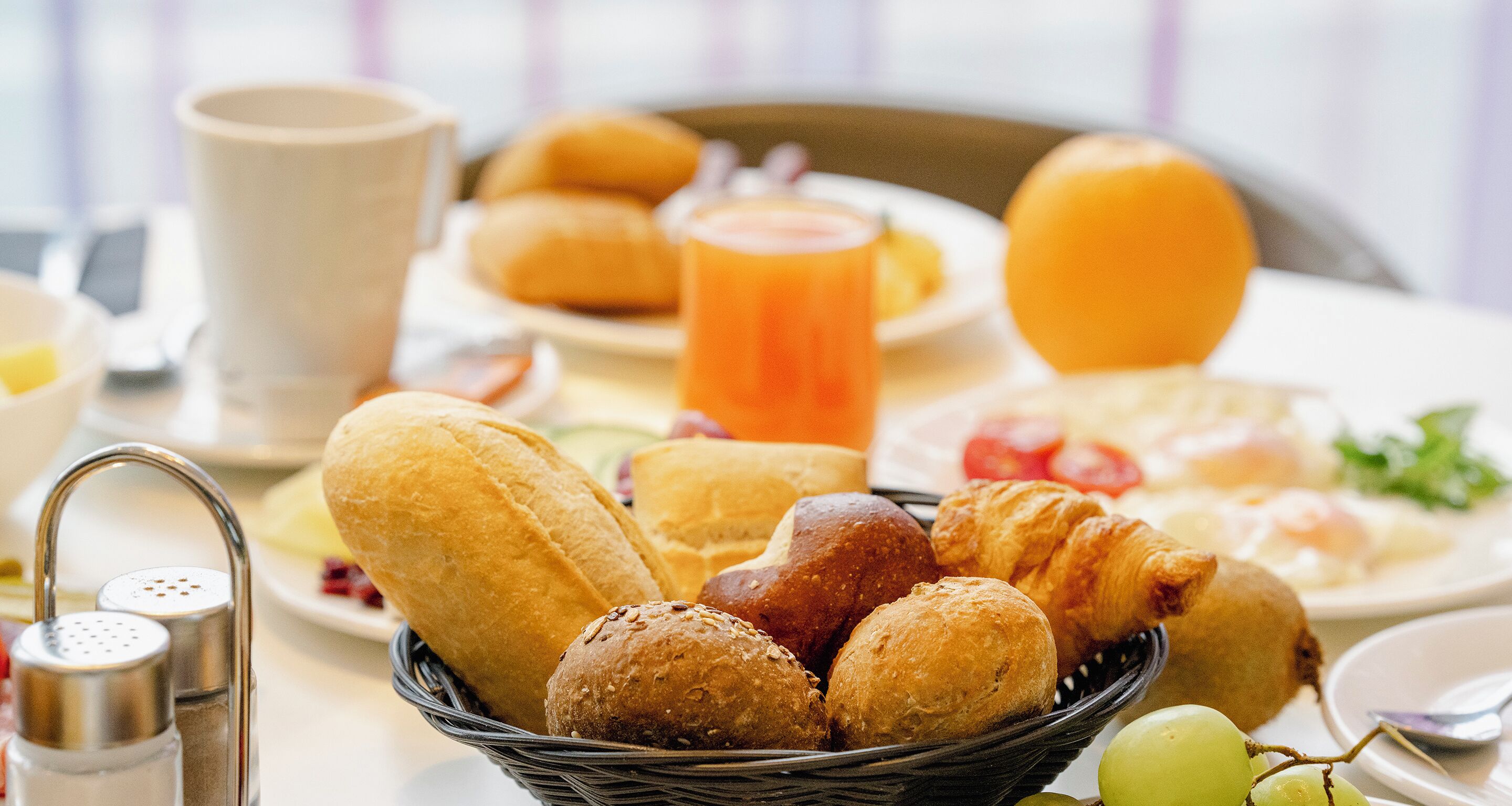 Ein Esstisch mit Brot, Gebäck und einer Obstschale.