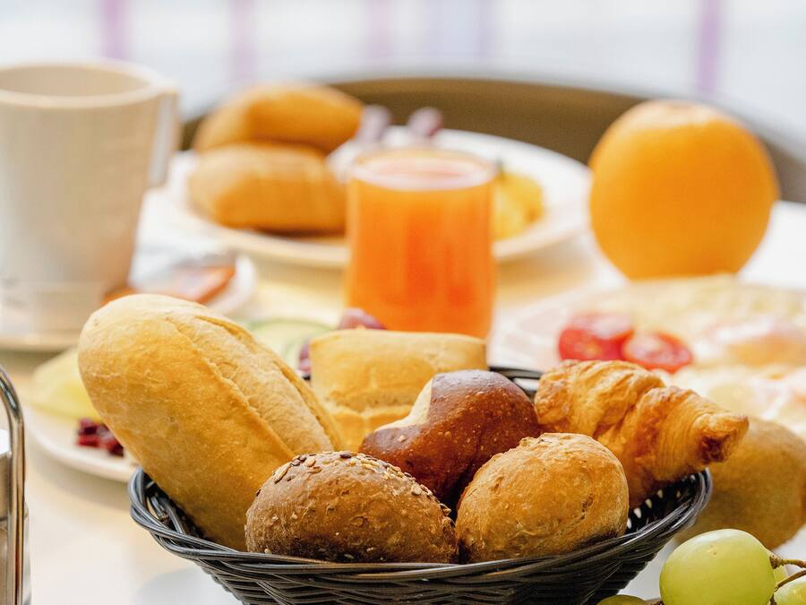 A breakfast table with bread, pastries, and a fruit bowl.