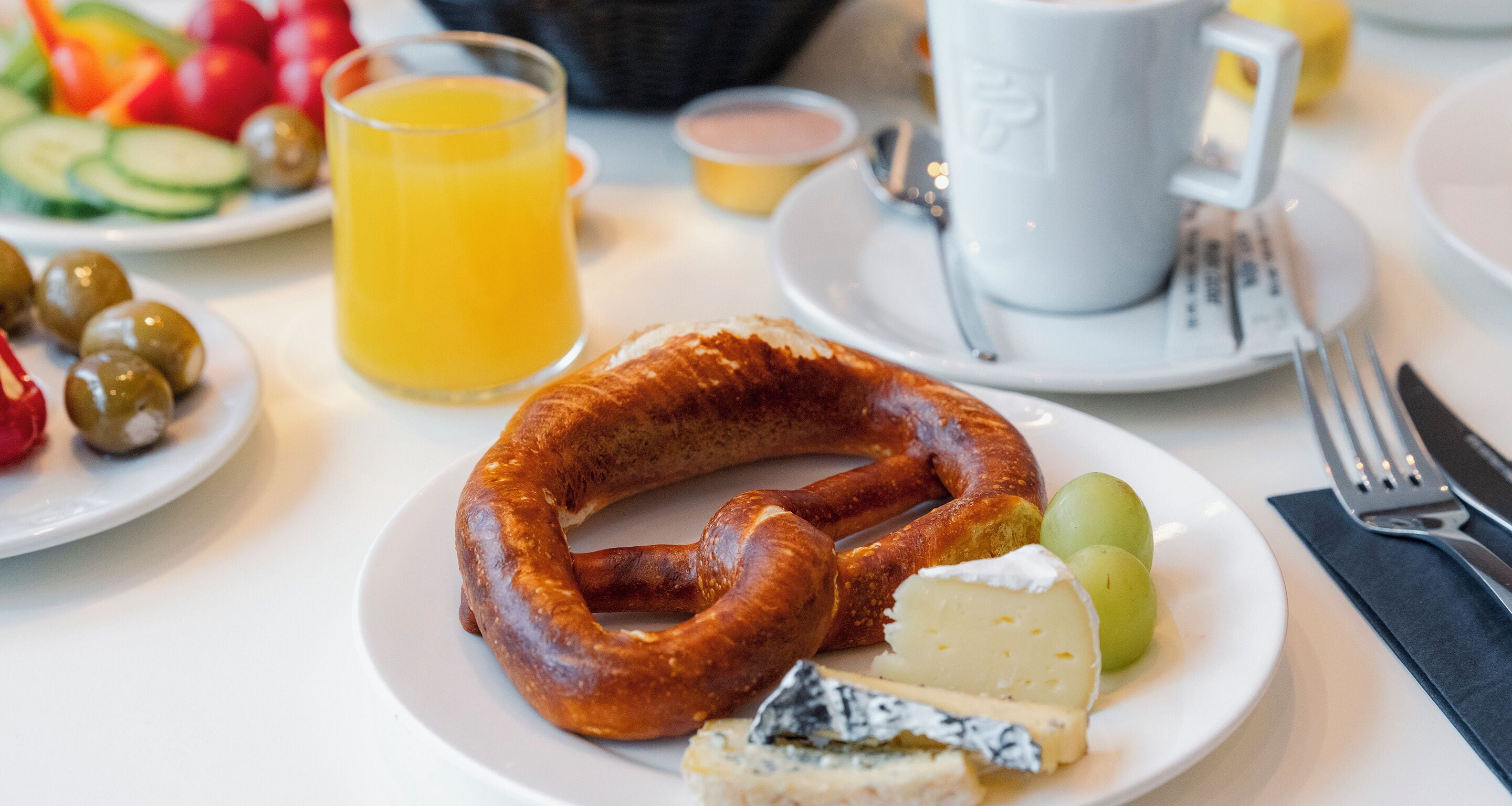 A plate with a sausage, cheese, and olives.