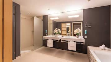 A modern bathroom with two sinks, a large mirror, and a bathtub.