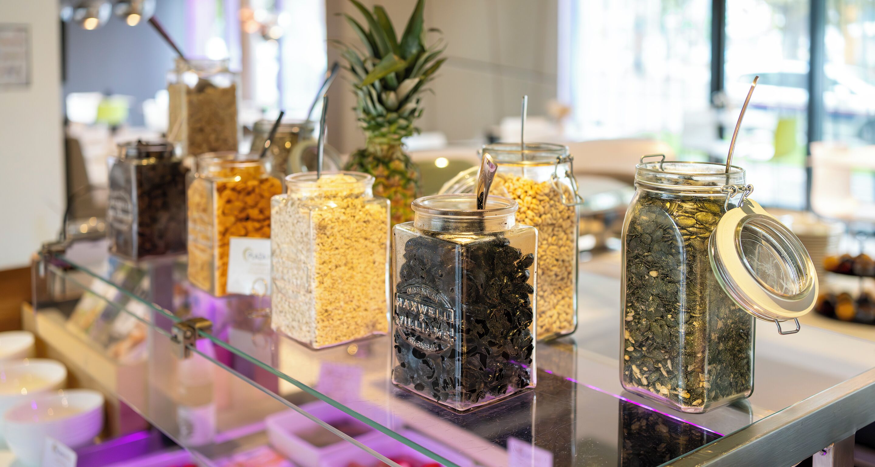 A display of various food items in glass jars on a glass counter.