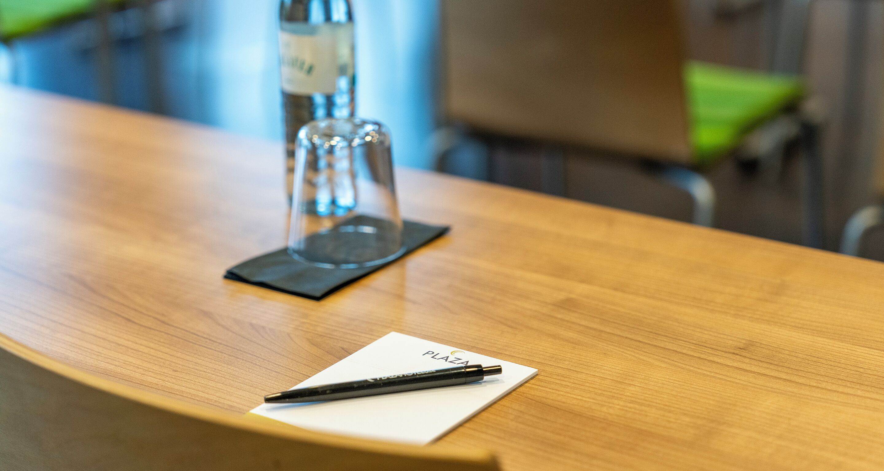 Una mesa de madera con una tarjeta blanca que dice "PLAZA" y un bolígrafo encima.